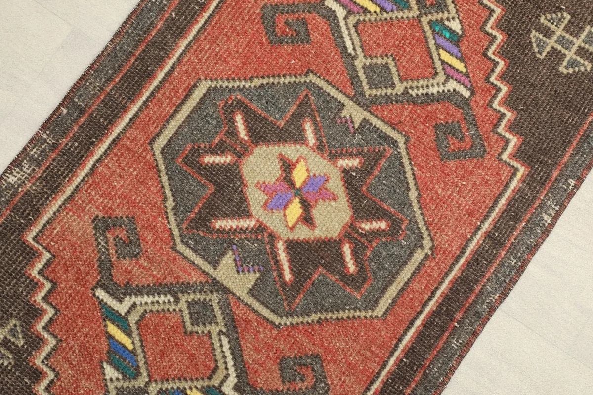 Close-up view of the rug's central medallion-like motif with rust, charcoal, yellow, and purple colors.