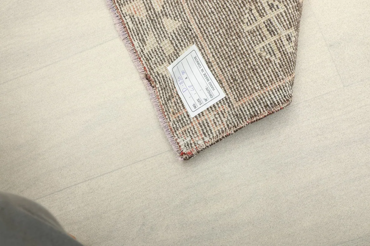 Close-up of the rug's back, showing the tightly woven cotton foundation and a product label.