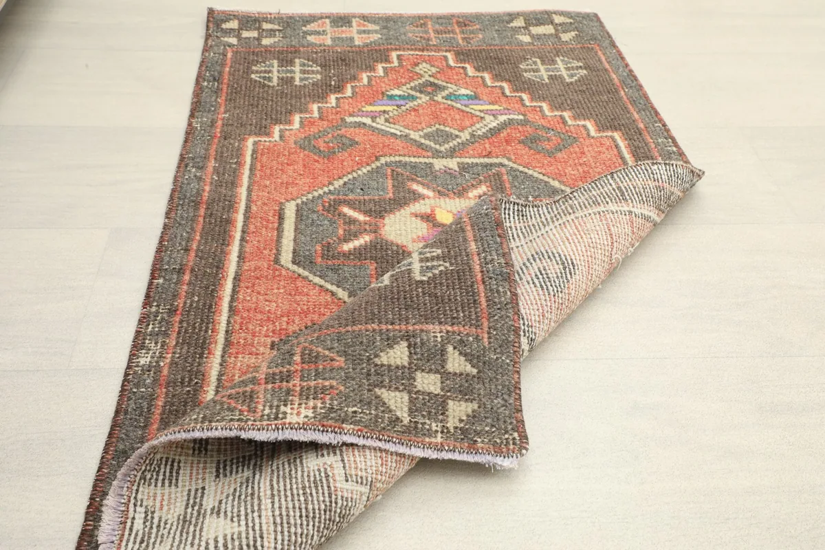 The rust doormat with one corner folded over, displaying the full design and the rug's flexibility.
