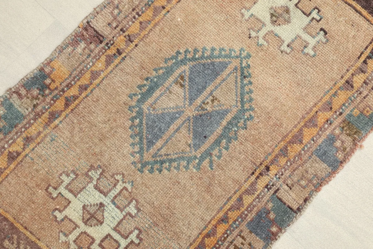 Close-up detail of the central geometric medallion in blue and beige against the tan field of the runner.