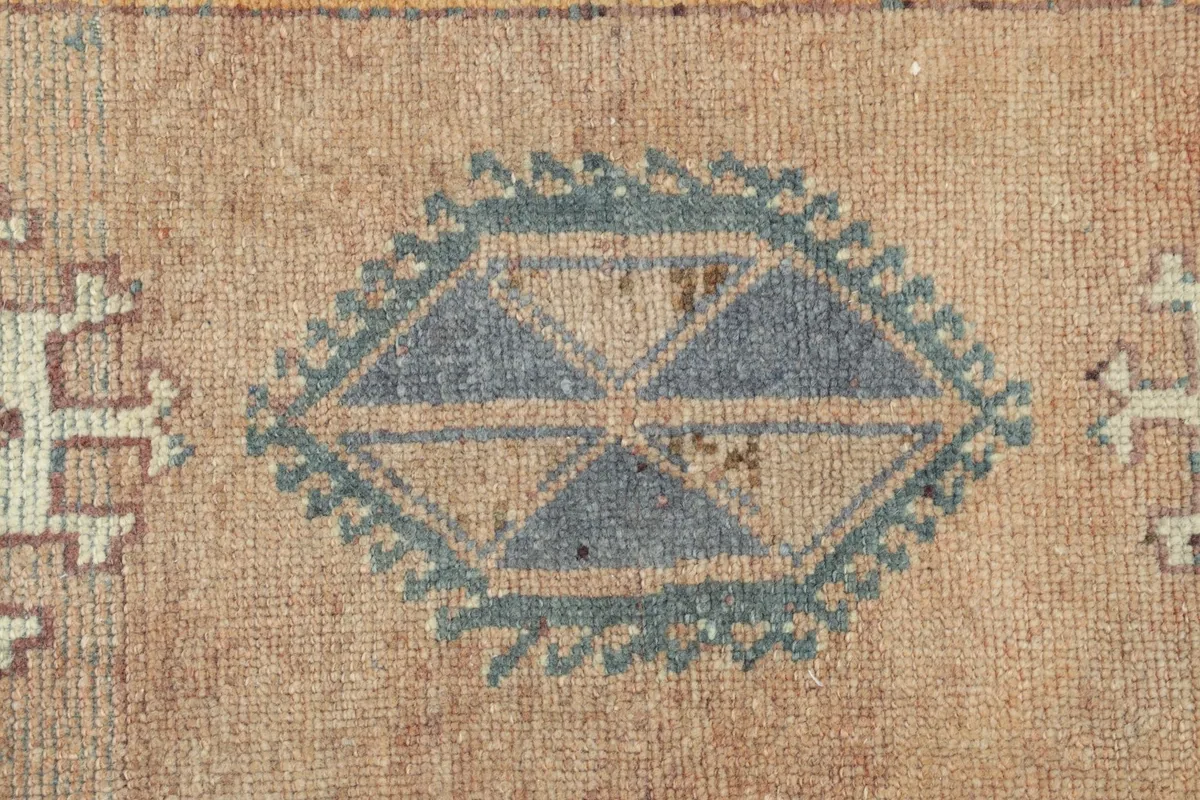 Detailed view of the intricate hand-knotted patterns and muted blue tones in the rug's central motif.