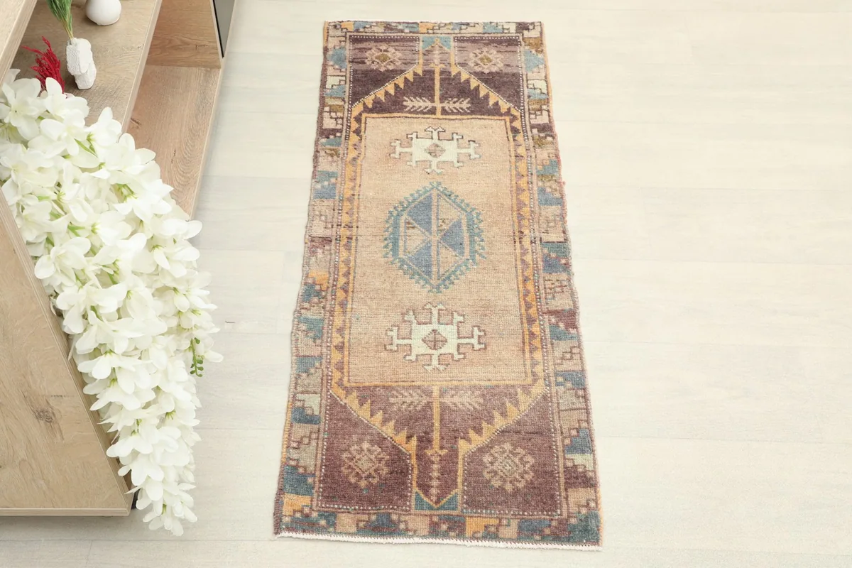 Overhead view of the hand-knotted wool runner, highlighting its central tan field and colorful border.