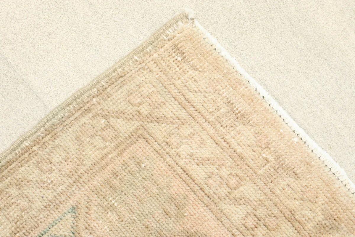 Corner detail showing the muted geometric border design and the finished edge of the rug.