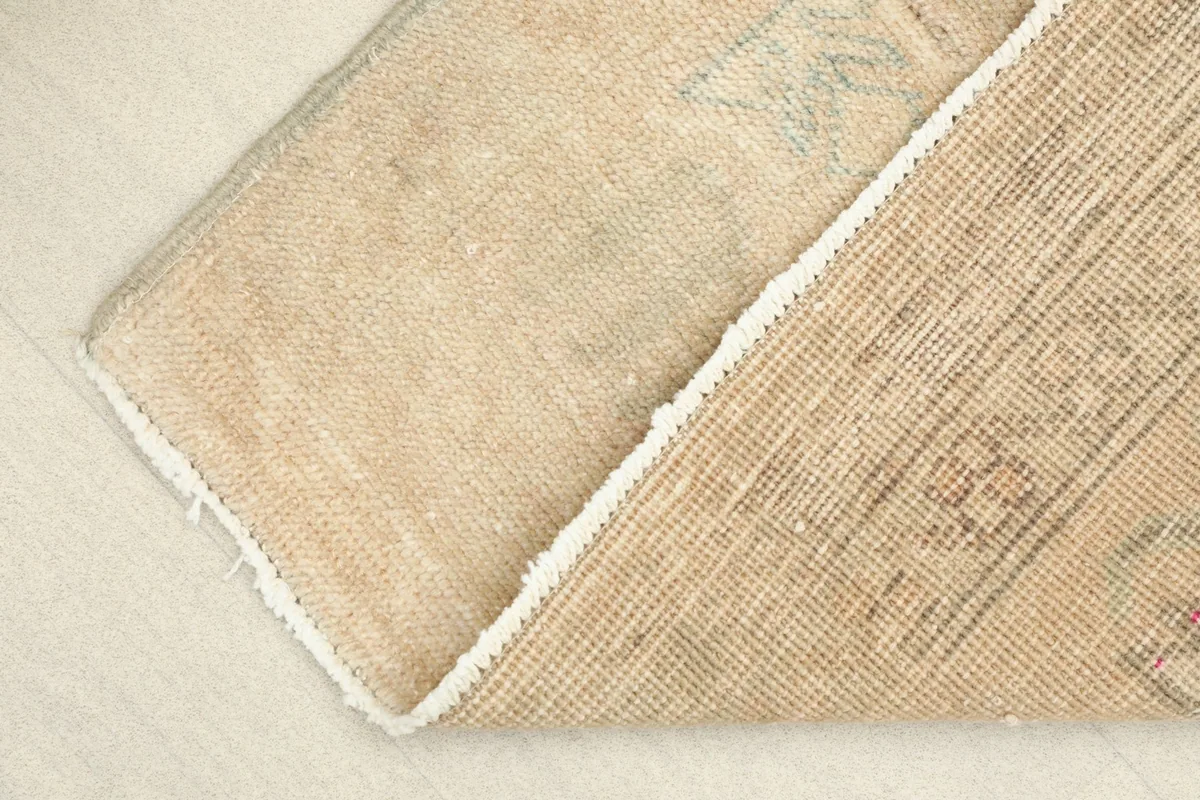 View of the back of the rug, folded to show the hand-knotted cotton foundation.