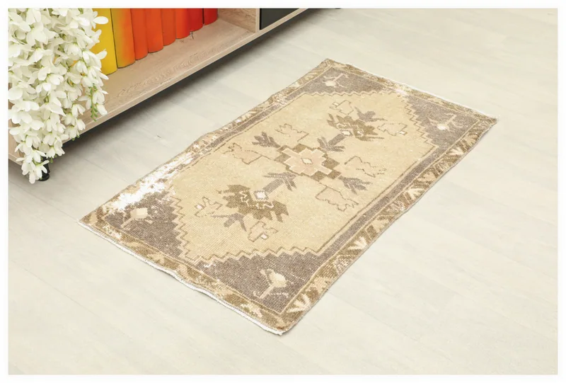 Full top view of the 1'10" x 3'3" vintage tan and brown geometric Anatolian rug on a white floor.