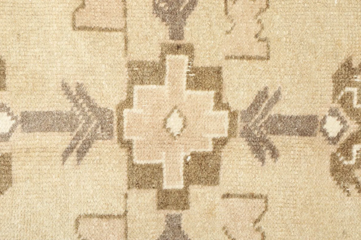 Close-up detail of the central geometric medallion-like motif in tan, brown, and charcoal tones.