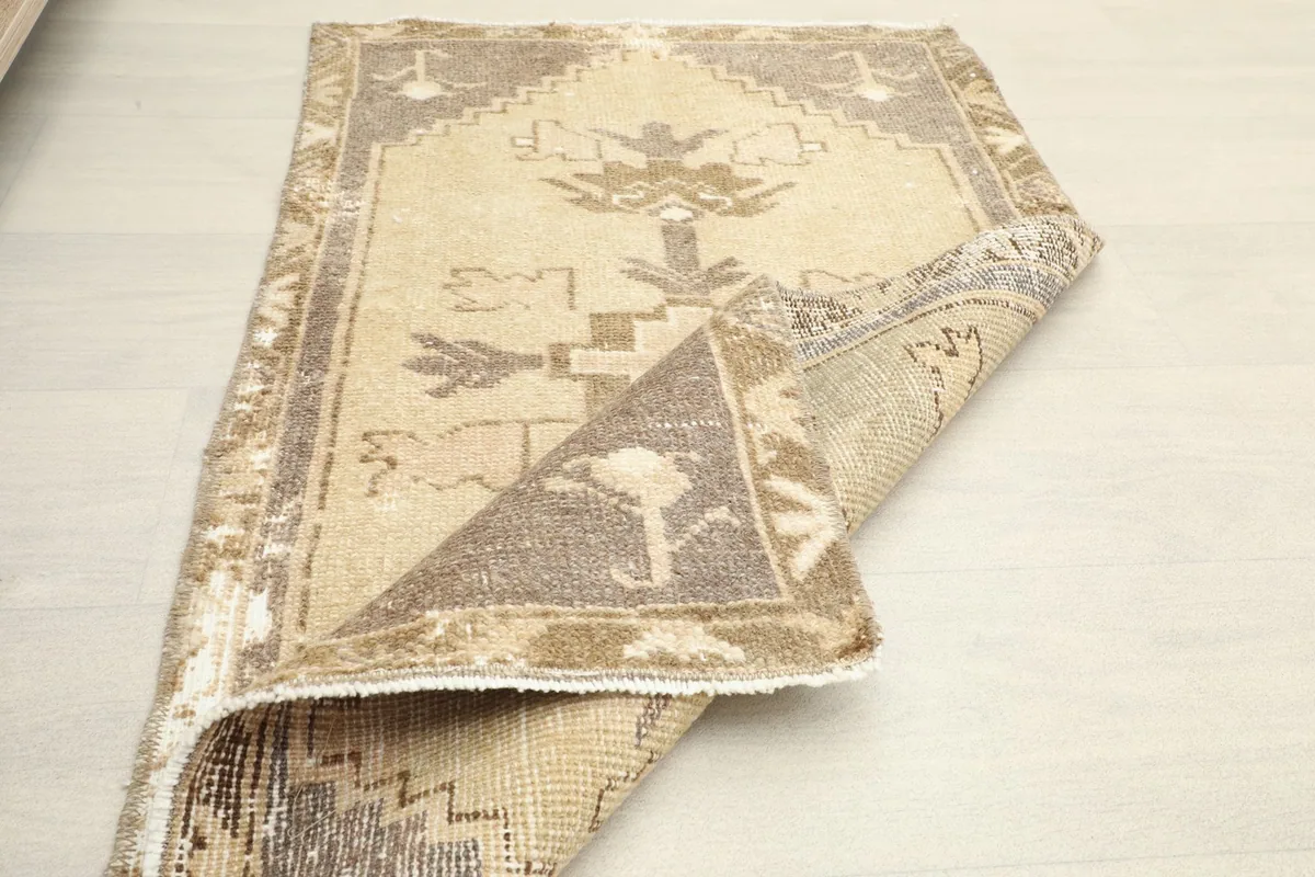 Partially folded rug displaying the full pattern on one side and the back of the rug on the other.