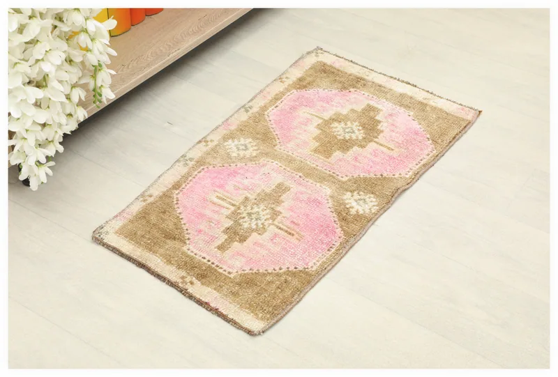 Full top view of the vintage pink and brown tribal Anatolian rug on a white floor