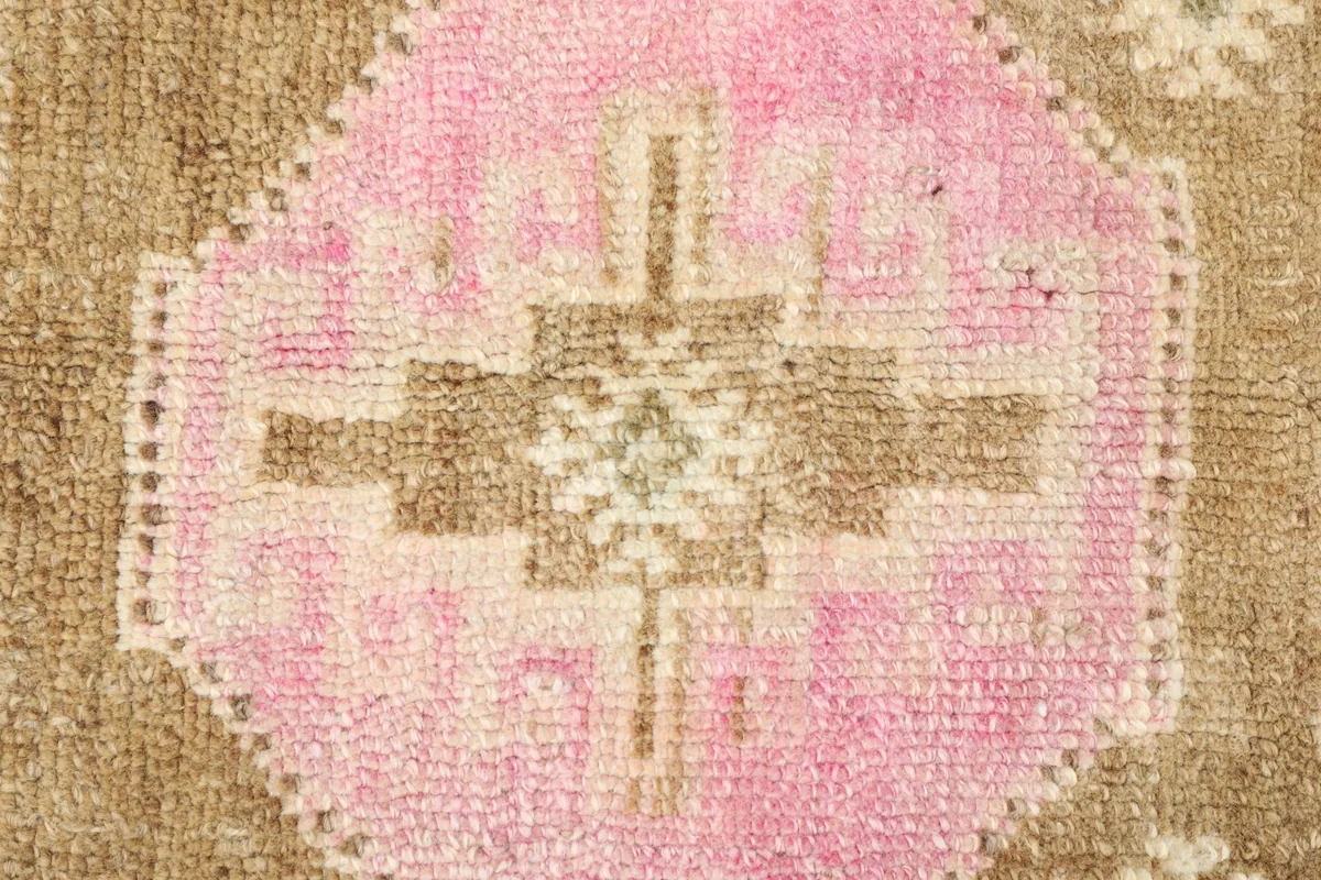Detailed view of a central pink medallion with a brown and cream geometric motif