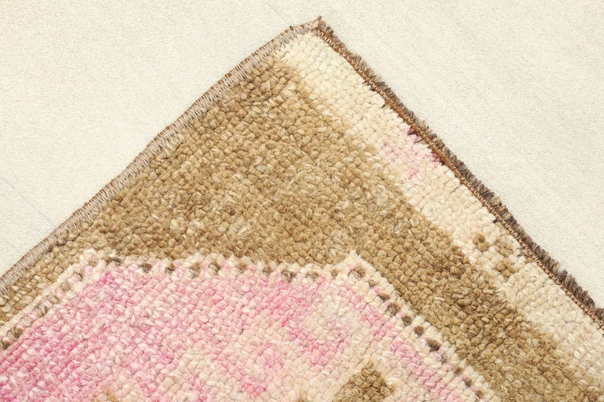 Close-up of the corner, showing the brown field, pink medallion edge, and cream border