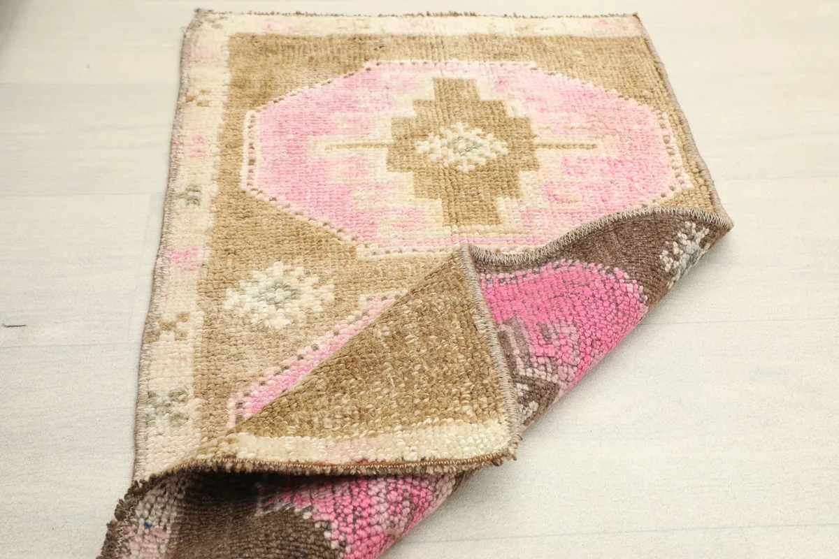 Rug folded to reveal the underside, showing the reverse of the pink and brown pattern