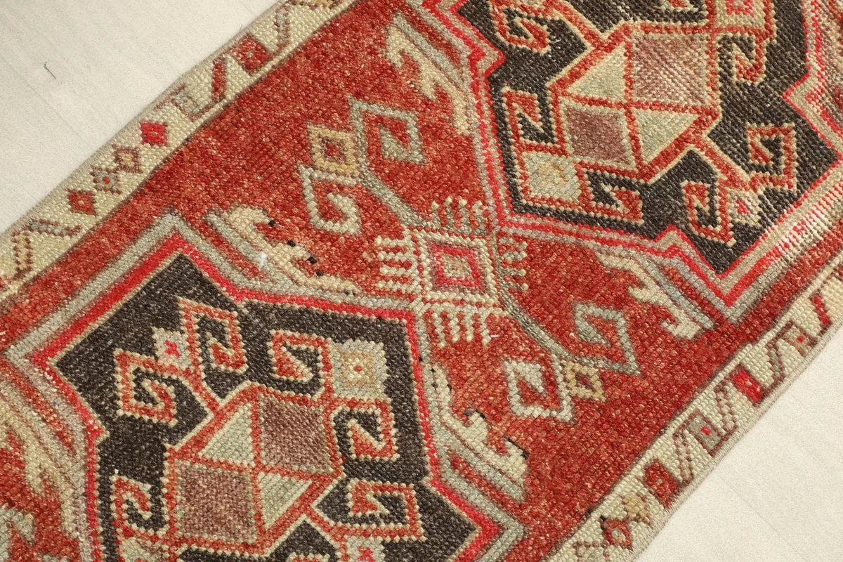 Close-up view of the rug's central design, showing the intricate black, red, and beige geometric patterns.