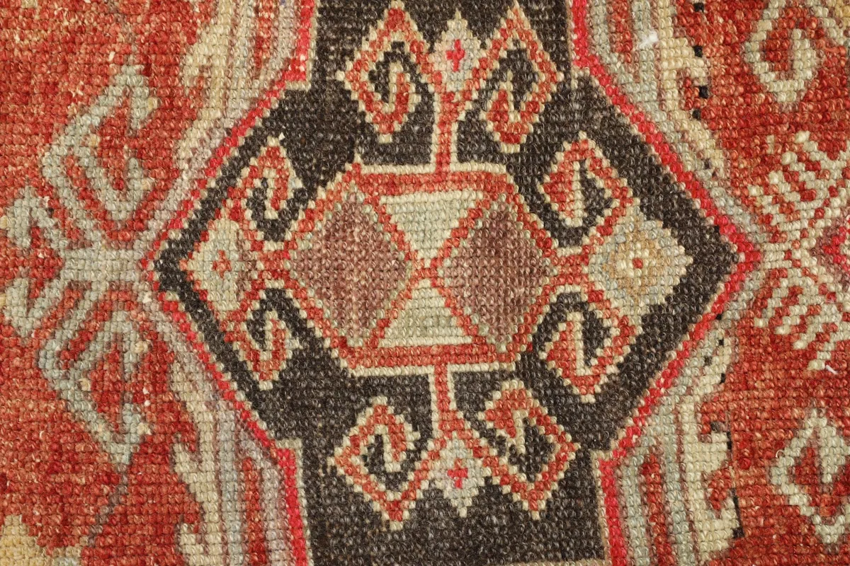 Detailed shot of a specific geometric motif within the rug, revealing the wool texture and color variations.