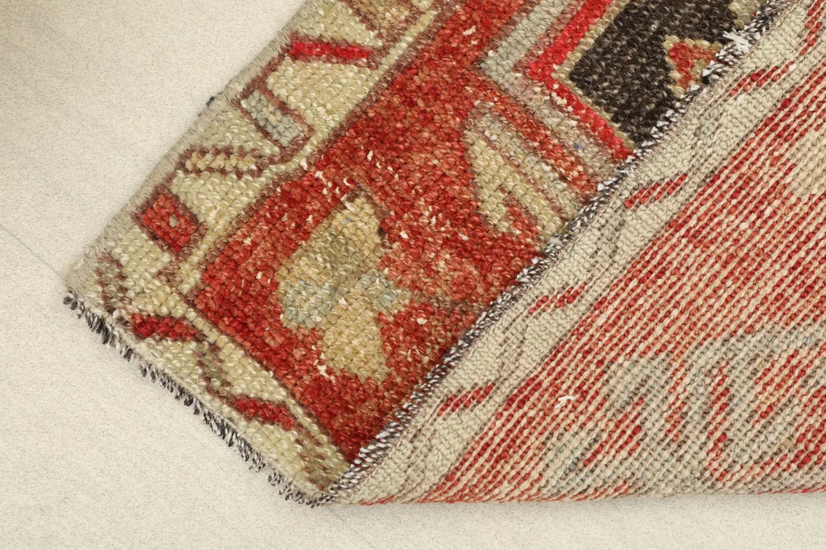 View of the rug's reverse side and a folded corner, revealing the cotton foundation and hand-knotting.