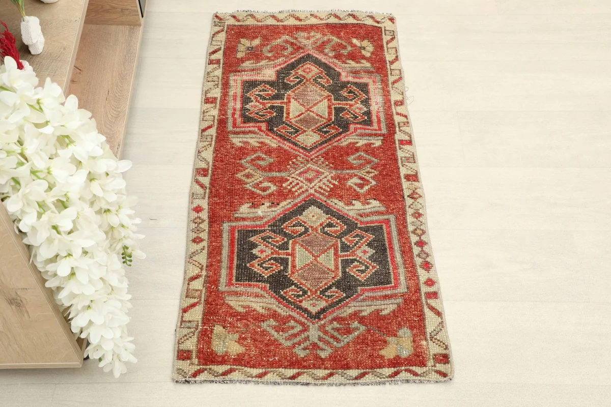 Direct overhead shot of the vintage Anatolian rug, highlighting its red field and black geometric motifs.
