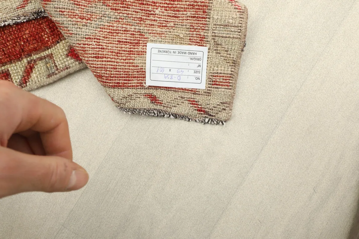 Close-up of the rug's label on the back, displaying size and material information, held by a hand.