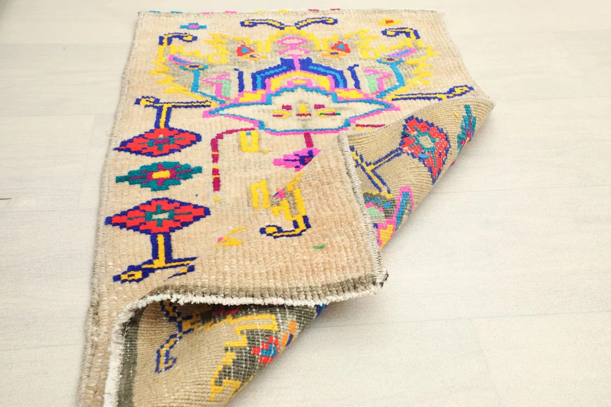 The rug with one corner folded back, revealing the reverse side and the construction details.