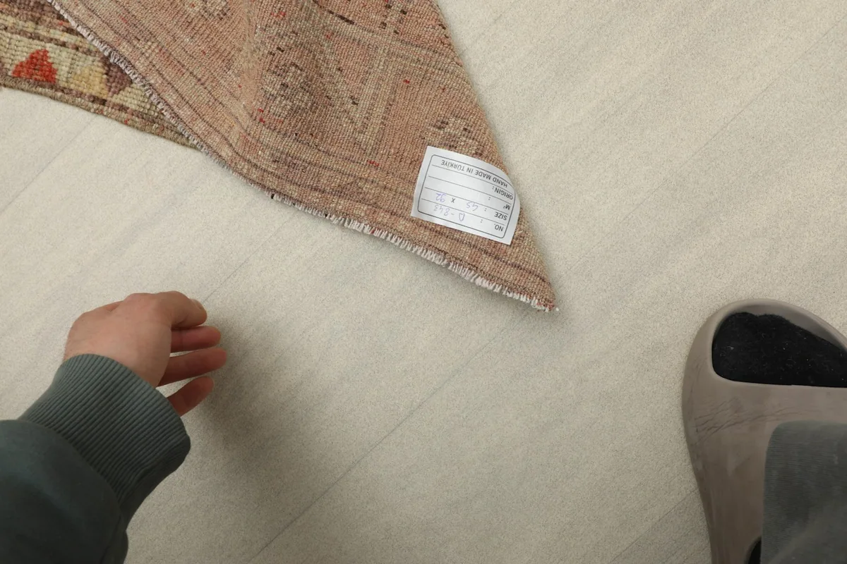 Close-up of the rug's backside, showing the cotton foundation and a product label.