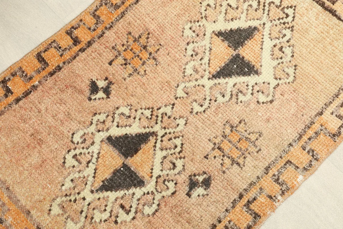 Angled close-up showing the texture and the central geometric patterns in black, ivory, and tan.