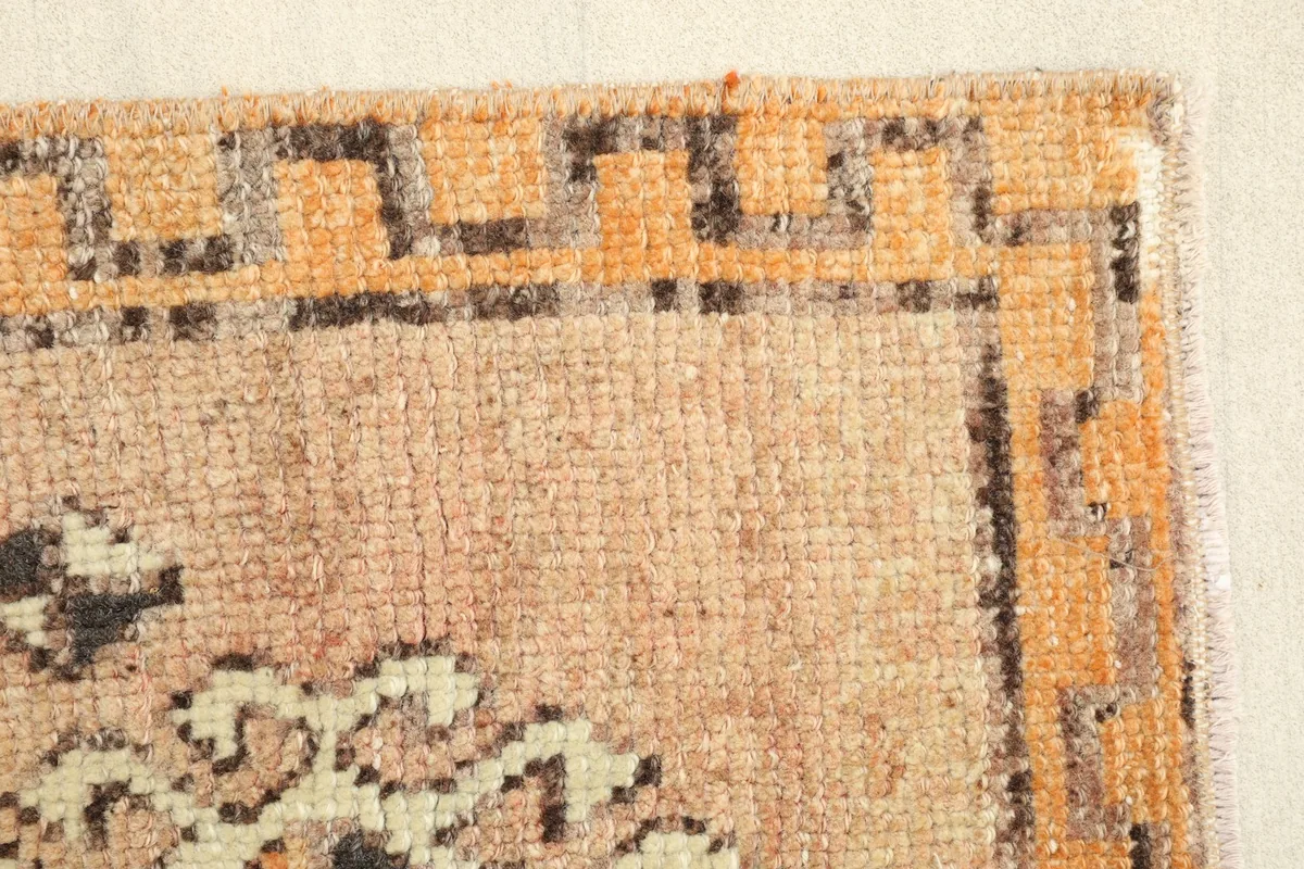 Close-up of the side border, showing the orange and black geometric design and the tan field.