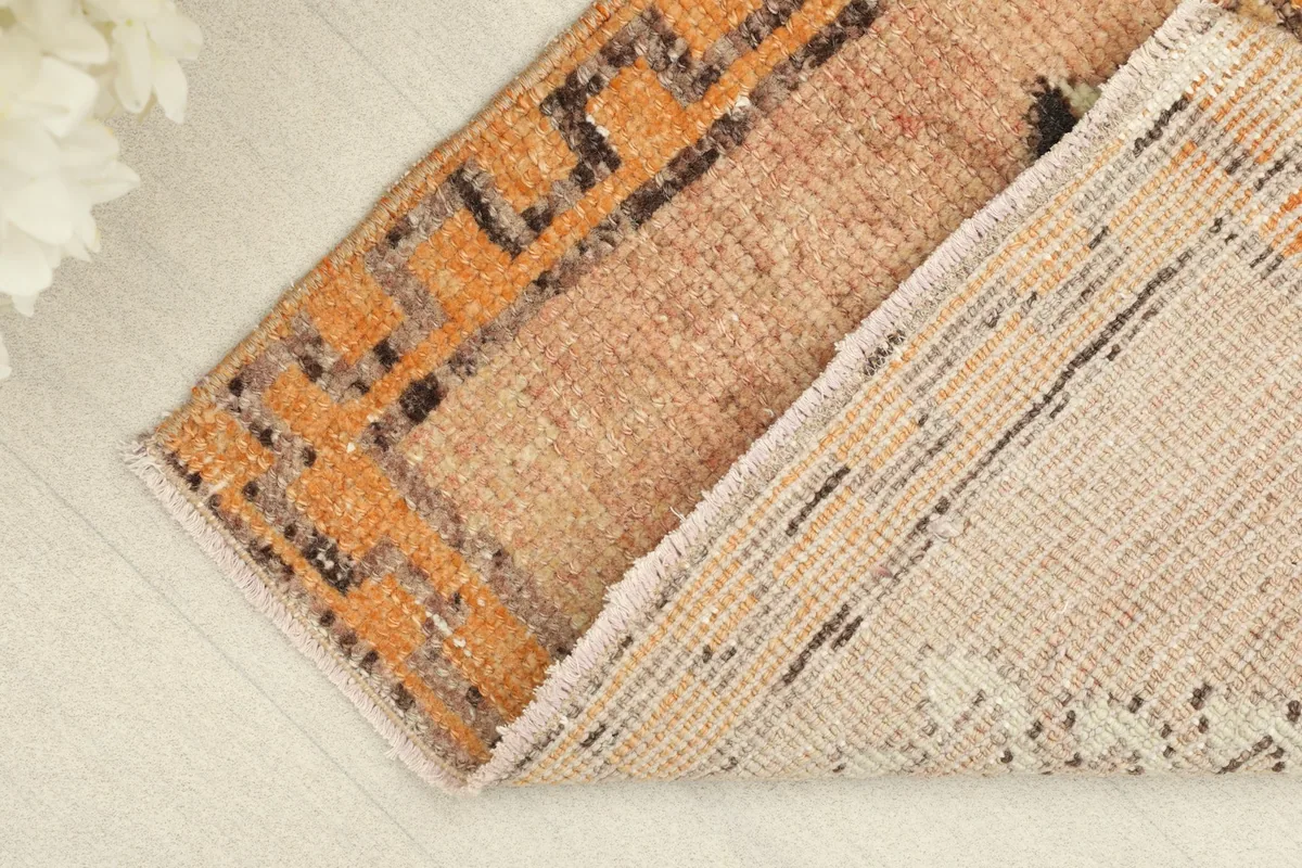 View of the rug folded to show the wool pile surface and the cotton foundation on the reverse side.