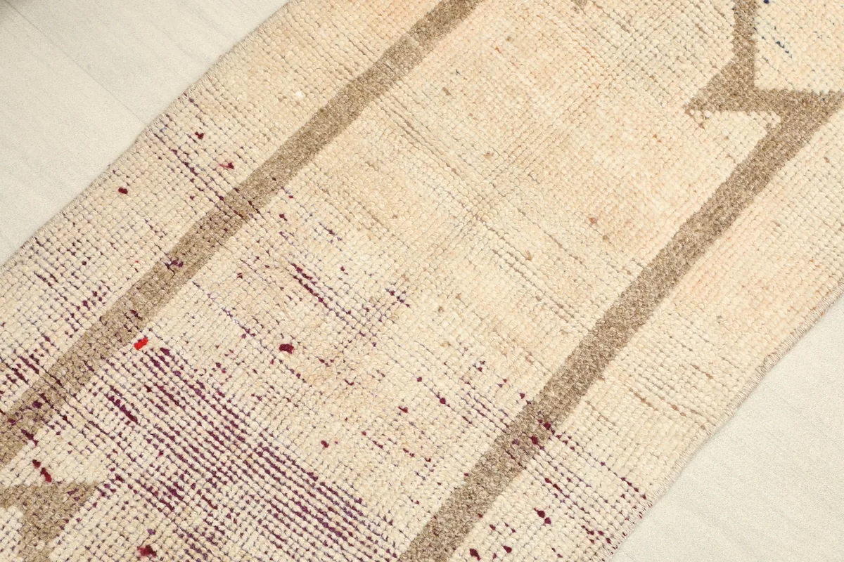 Close-up detail of the ivory field and brown geometric pattern, showing the low pile and texture.