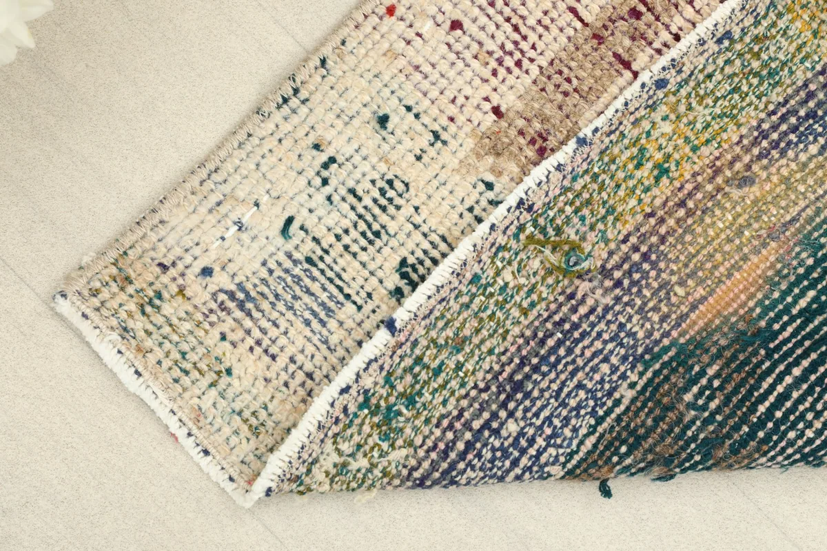 View of the rug folded to show the back, revealing the intricate hand-knotted cotton foundation.
