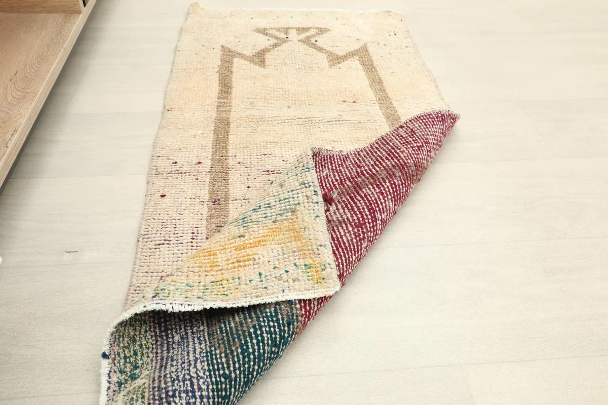 Rug partially folded, displaying both the top design and the tightly woven back of the vintage piece.