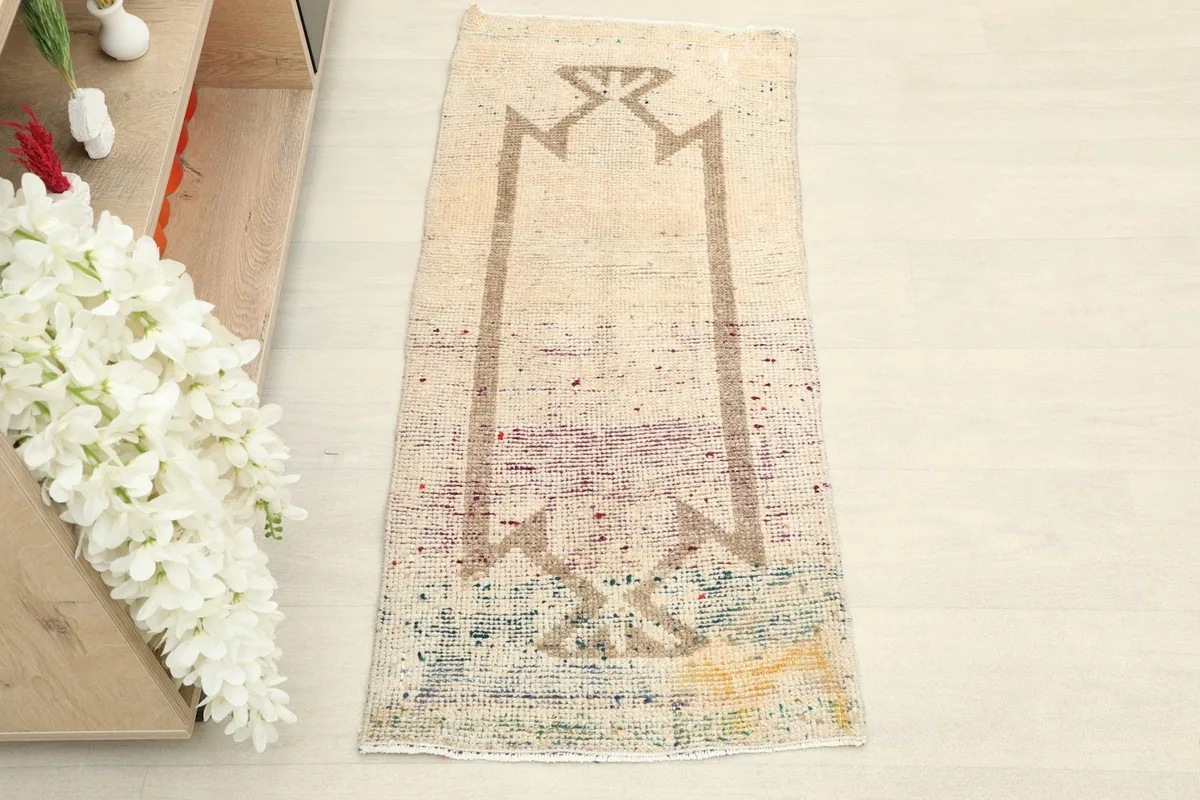 Overhead view of the ivory geometric prayer rug, highlighting its full design and distressed multicolor end.