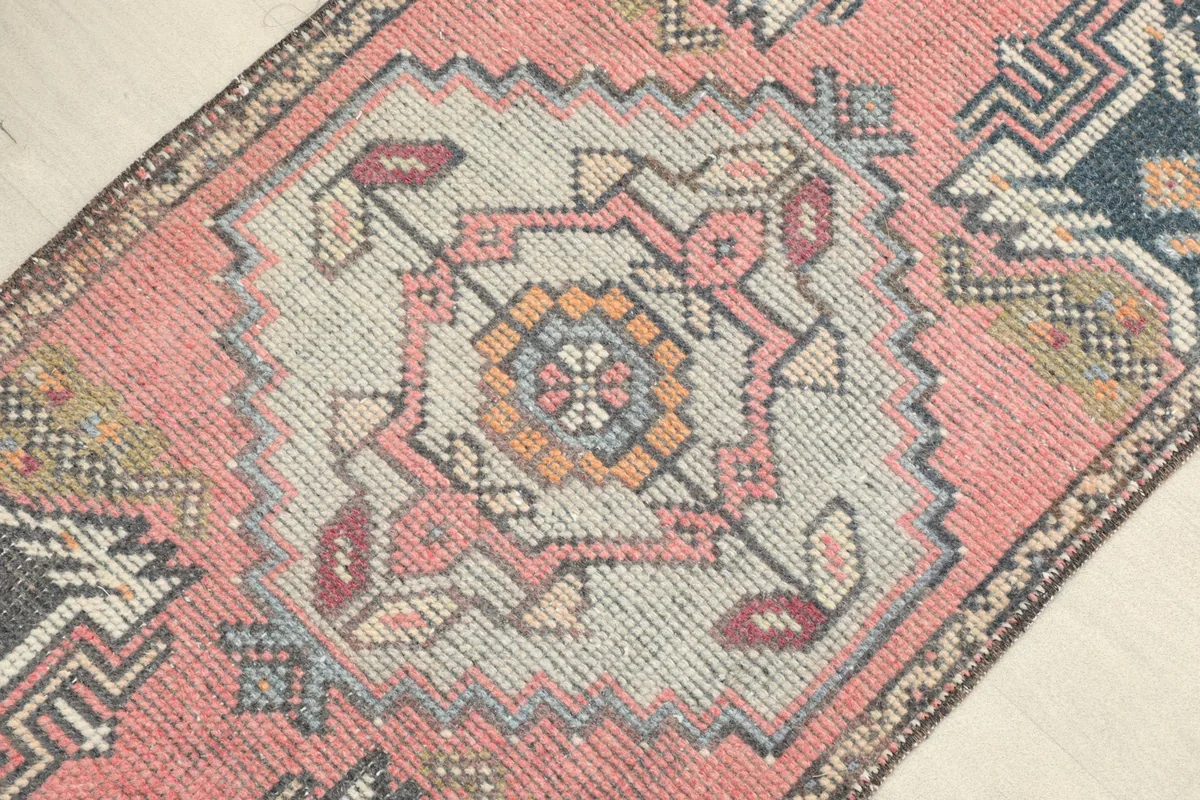 Close-up detail of the central gray medallion with orange and blue accents on the rose field.