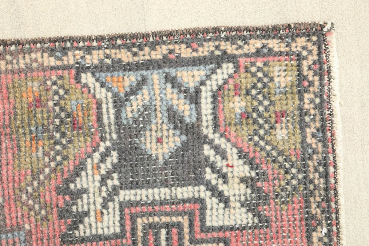 Close-up of a tribal motif in gray and black, showing the hand-knotted wool pile texture.
