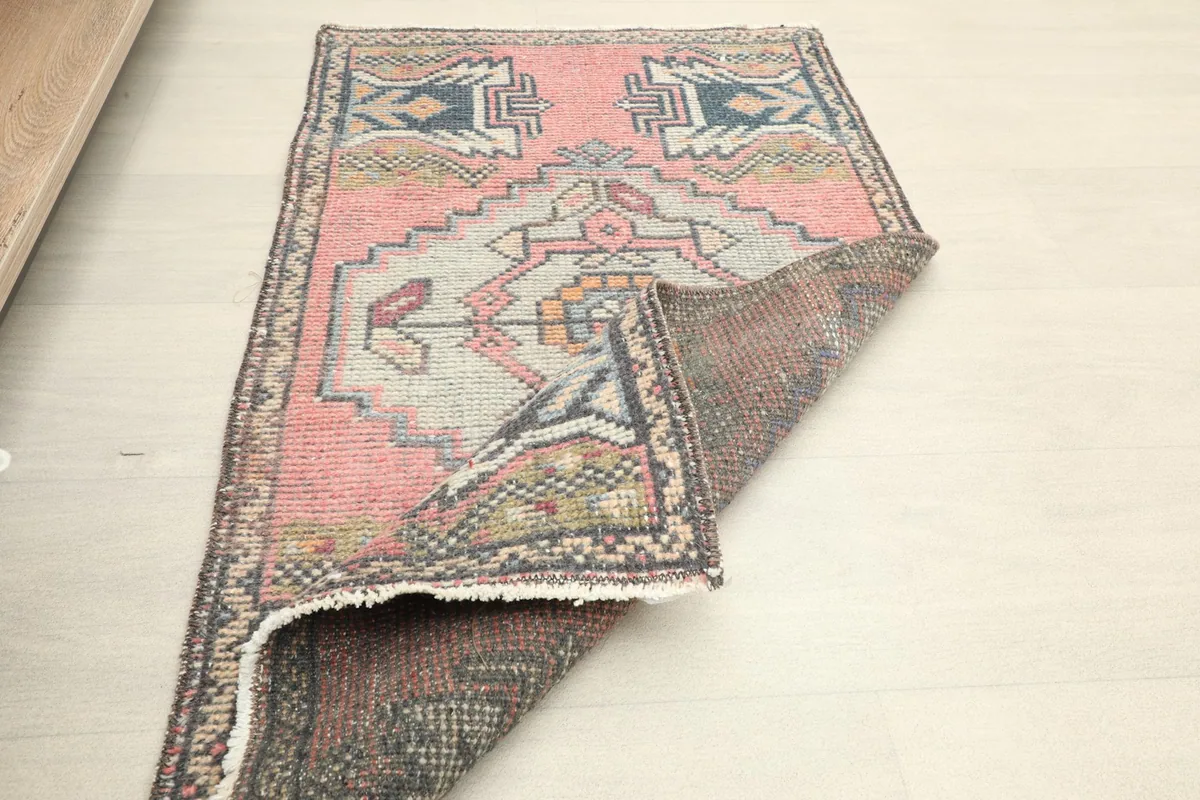The rug partially folded on the floor, showing its size and the underside texture.