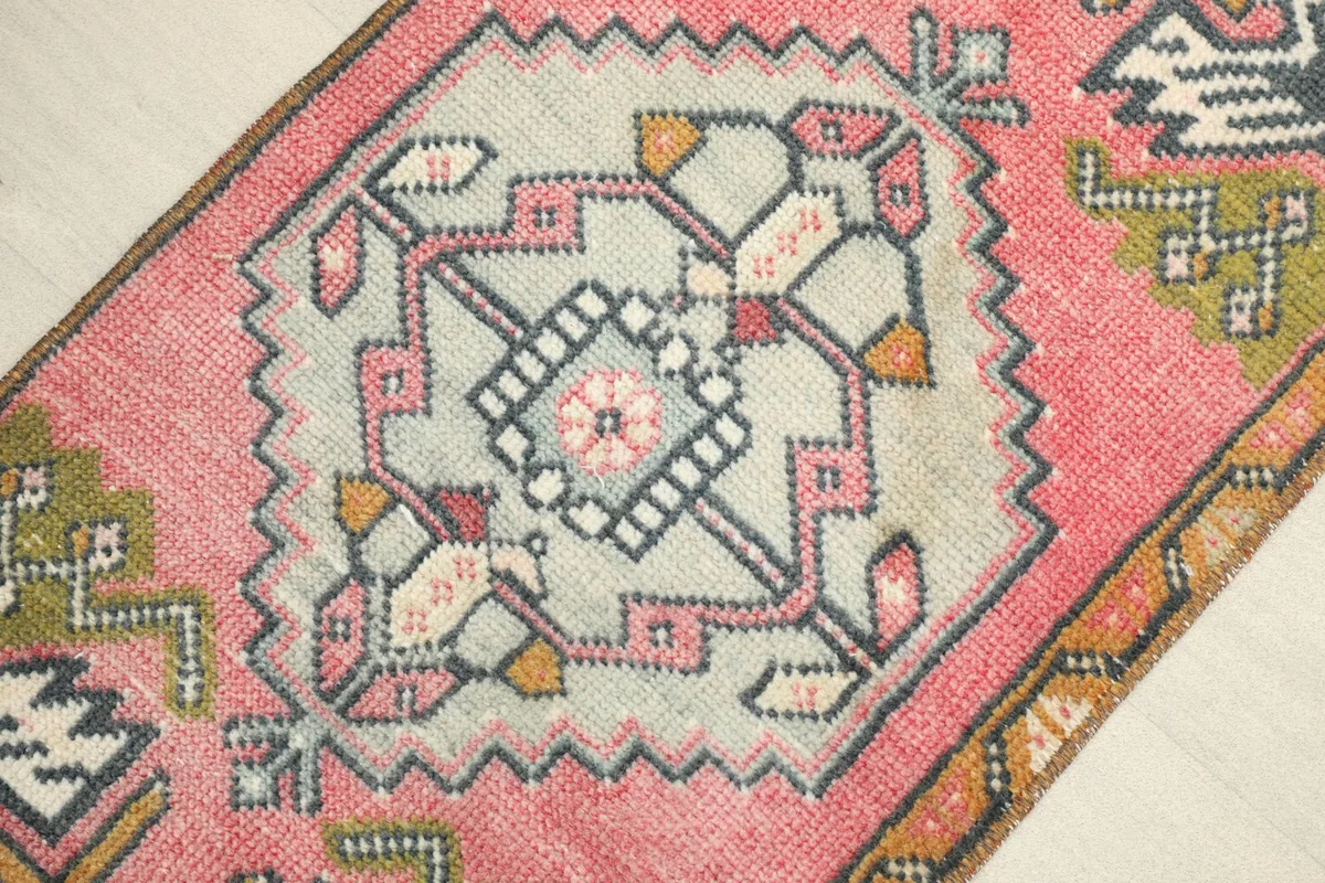 Close-up detail of the central geometric medallion with rose, olive, gray, and gold tones.