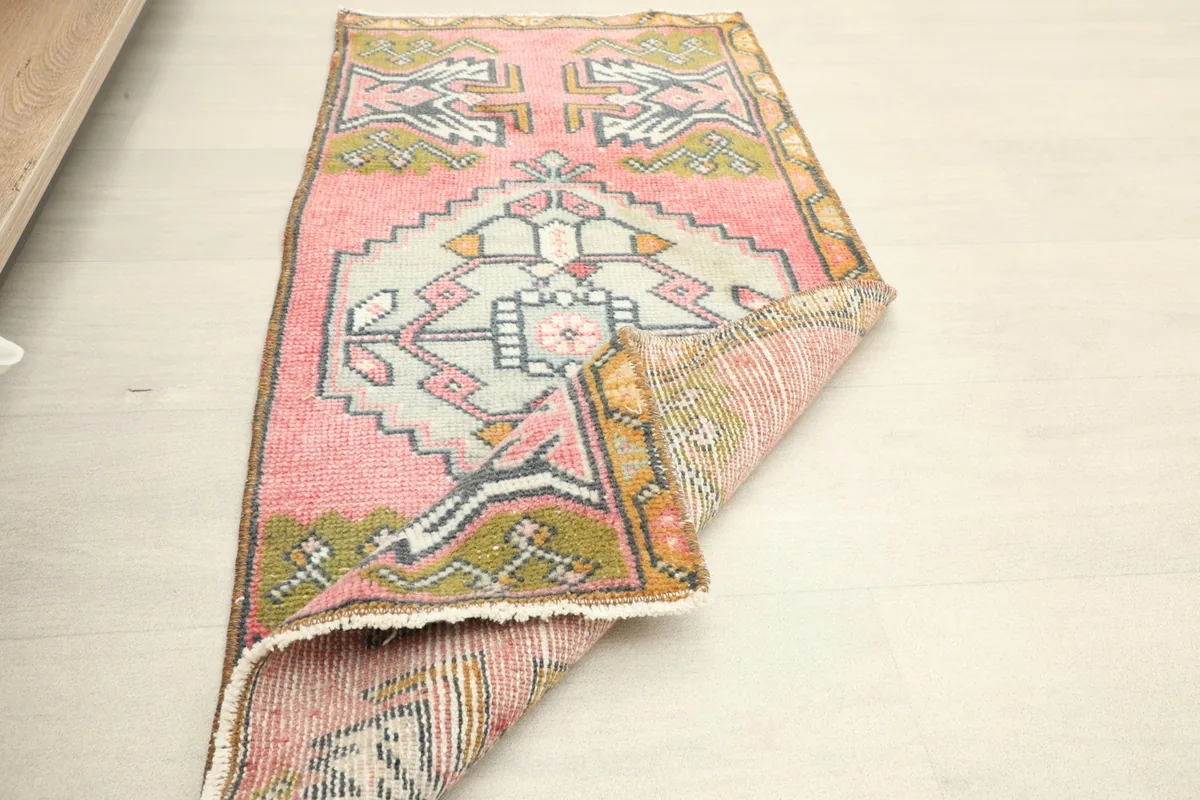 Angled view of the rug with a corner folded, highlighting its texture and vintage condition.