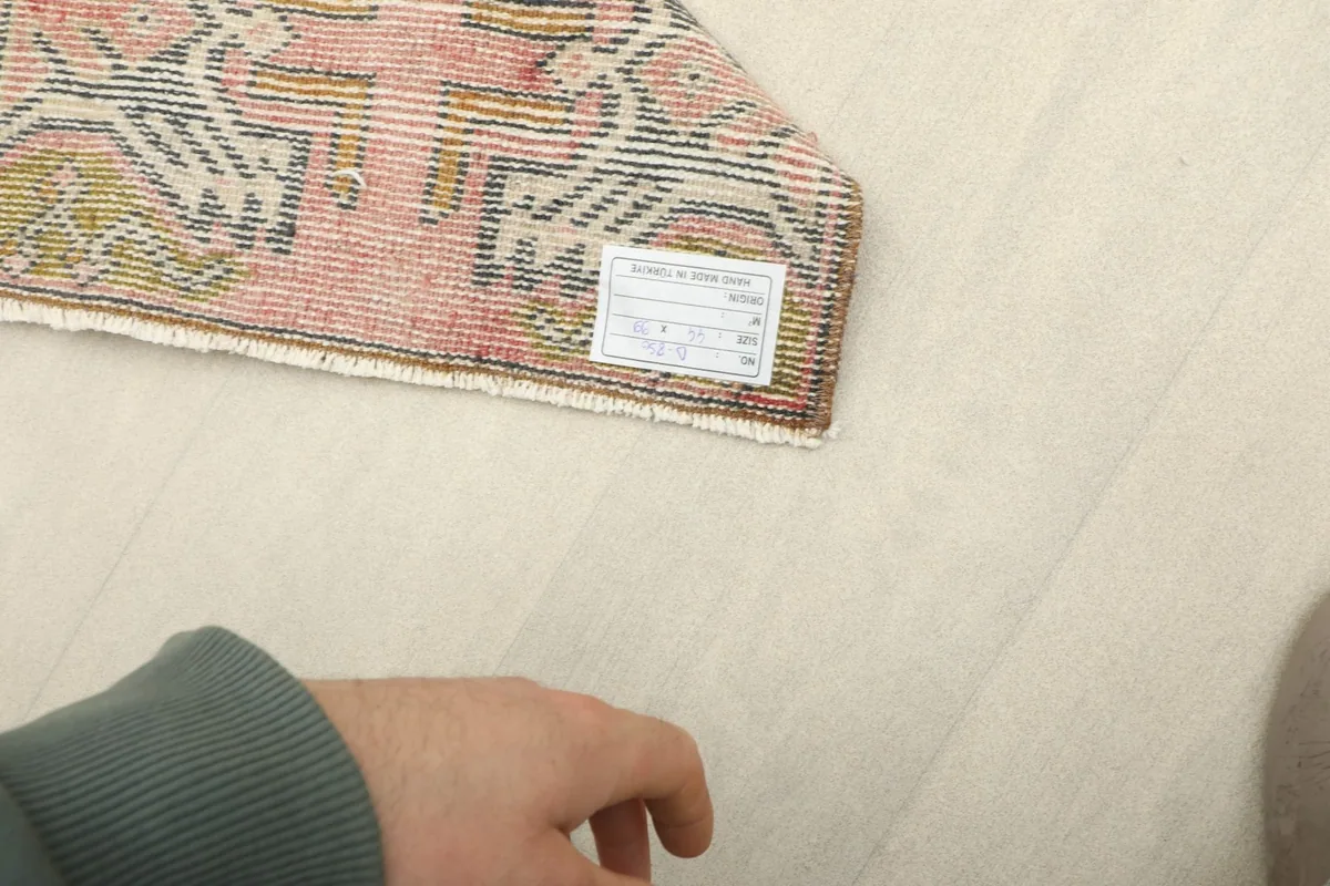 Hand pointing to the care label on the back of the vintage Anatolian wool rug.