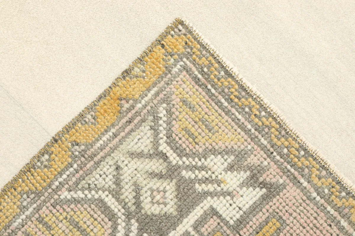 Angled view showing the corner of the rug with its yellow border and geometric designs