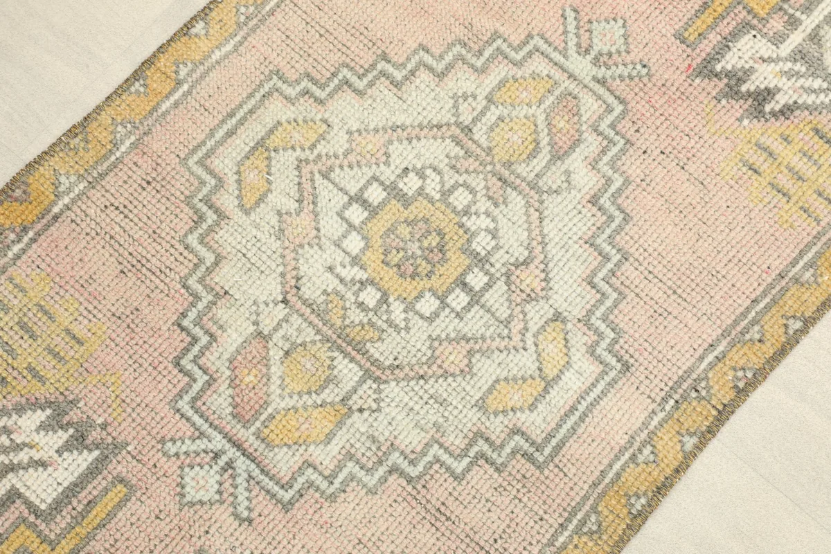 Close-up view of the central geometric medallion and surrounding patterns in pink, yellow, and gray