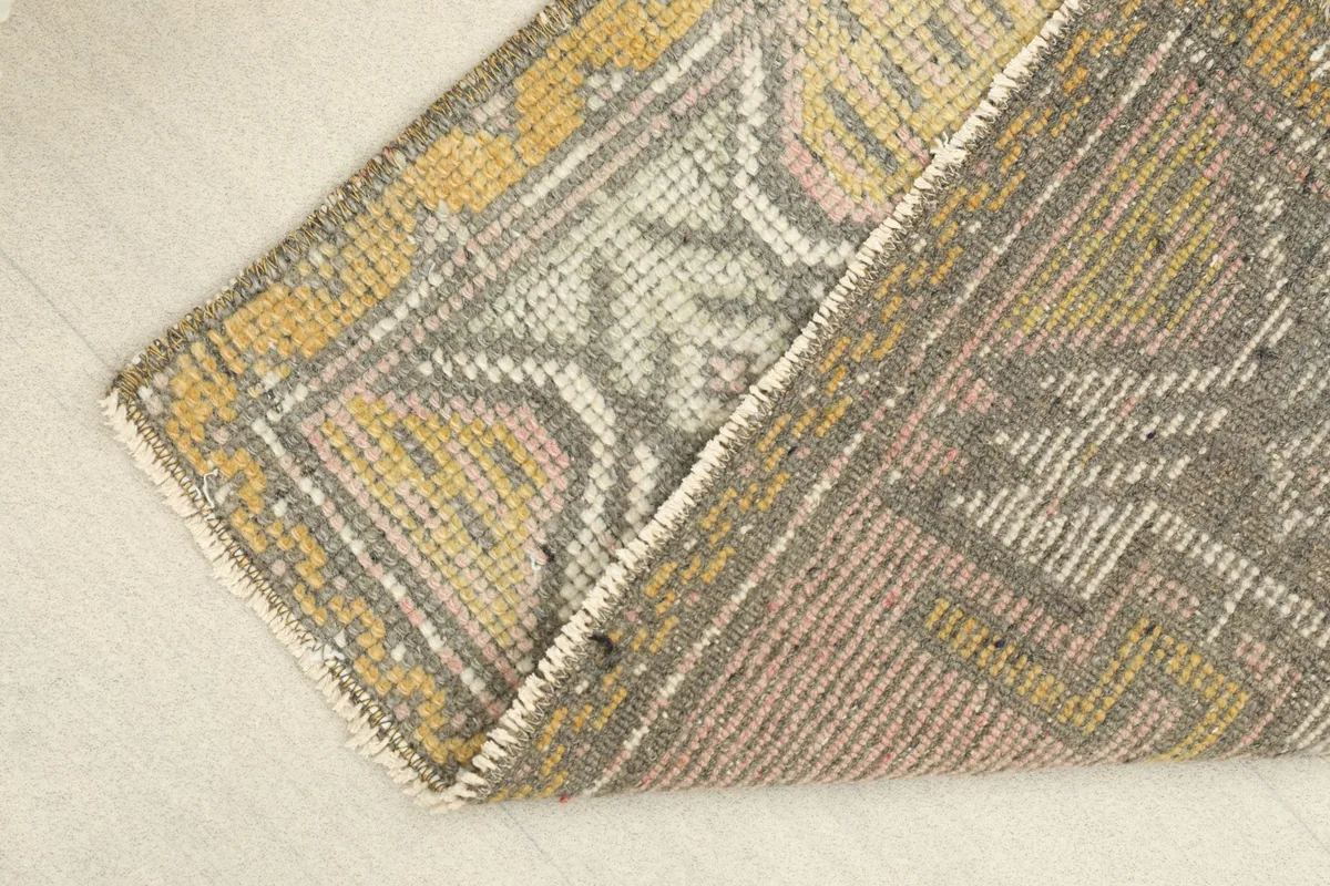 View of the rug folded to show the low wool pile and hand-knotted texture
