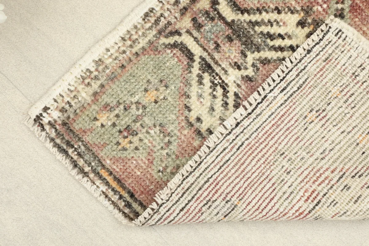 Corner lifted to reveal the hand-knotted cotton foundation and reverse side of the rug.