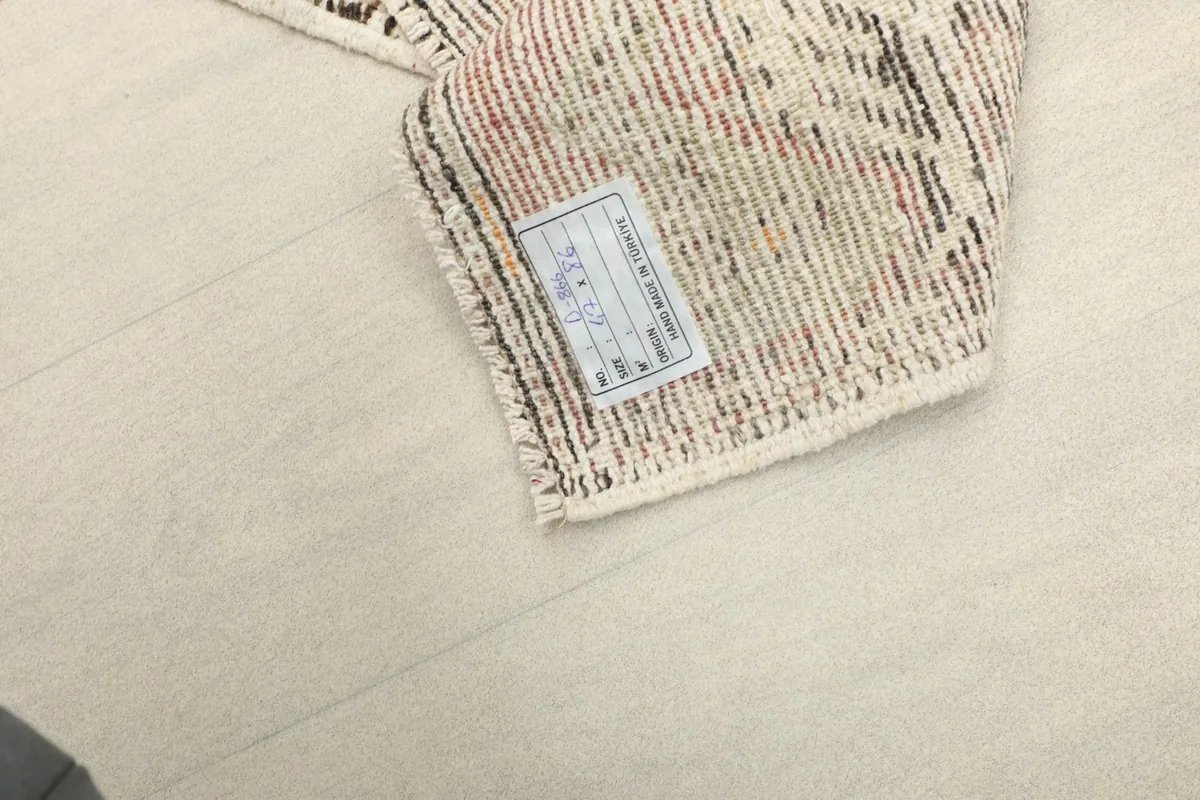 Close-up of the back of the rug with its tag, showing the tightly woven cotton foundation.