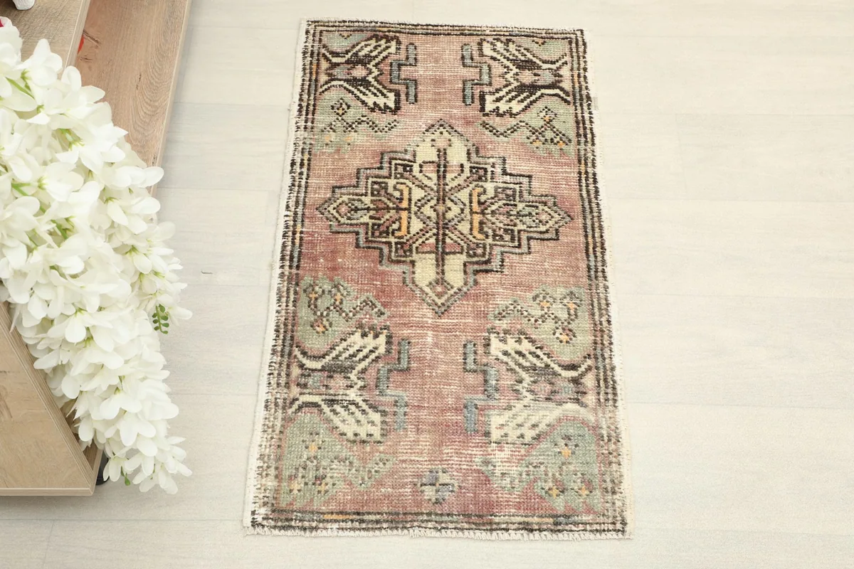 Overhead view of the hand-knotted rose and green tribal doormat.