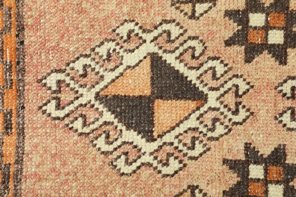 Detailed view of a single brown and orange diamond motif with ivory tribal outlines