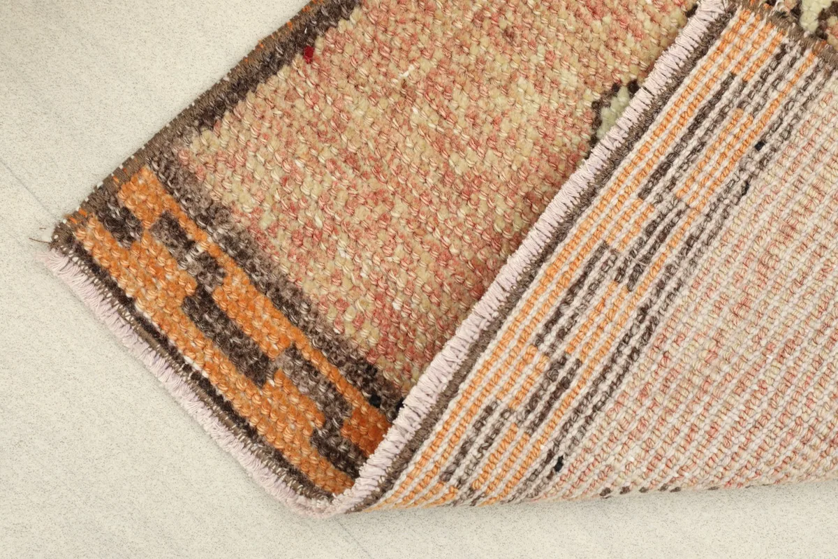 View of the rug folded to show the cotton foundation and the reverse side of the hand-knotting