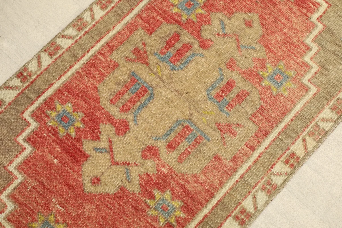 Close-up view of the rug's central design, highlighting the rust, tan, blue, and yellow geometric motifs.