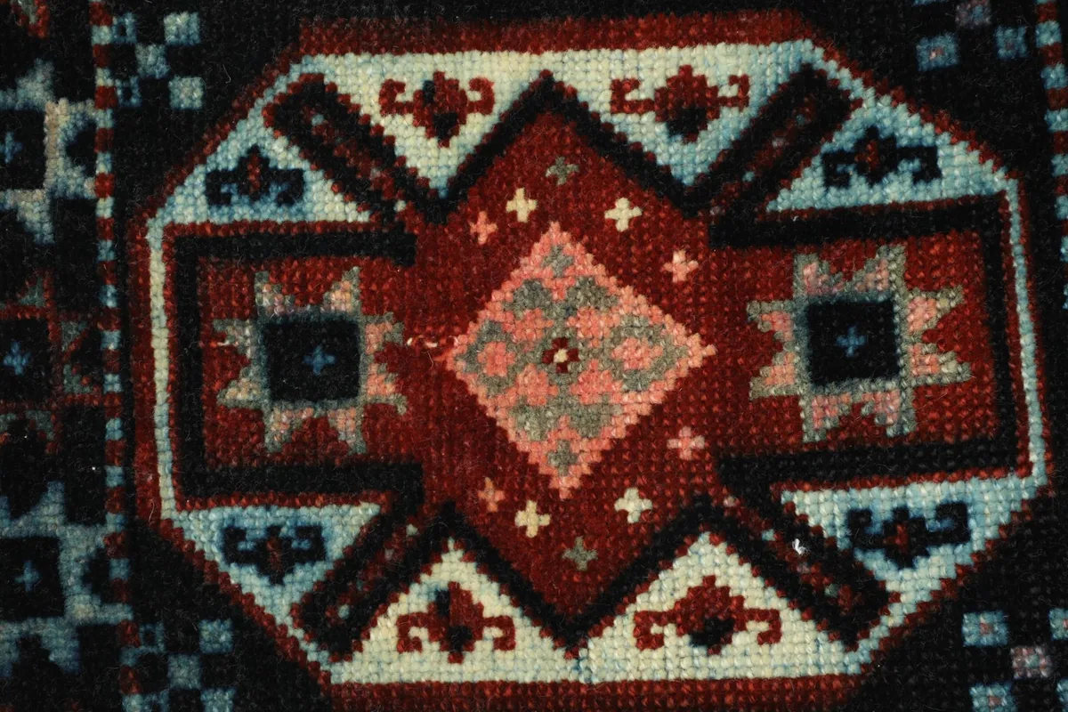 Close-up detail of the central red medallion and surrounding blue and ivory patterns