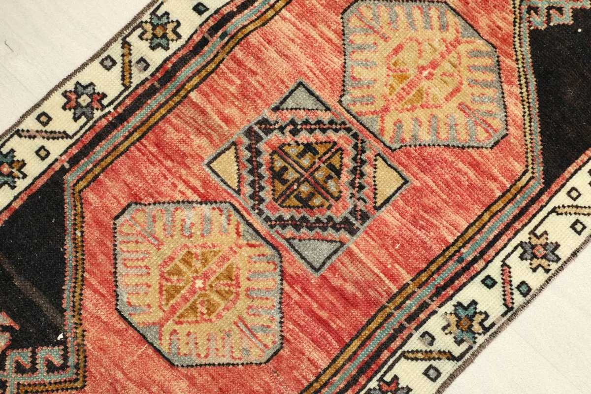 Close-up detail of the rug's central rose field with geometric gold and gray patterns and a black border.