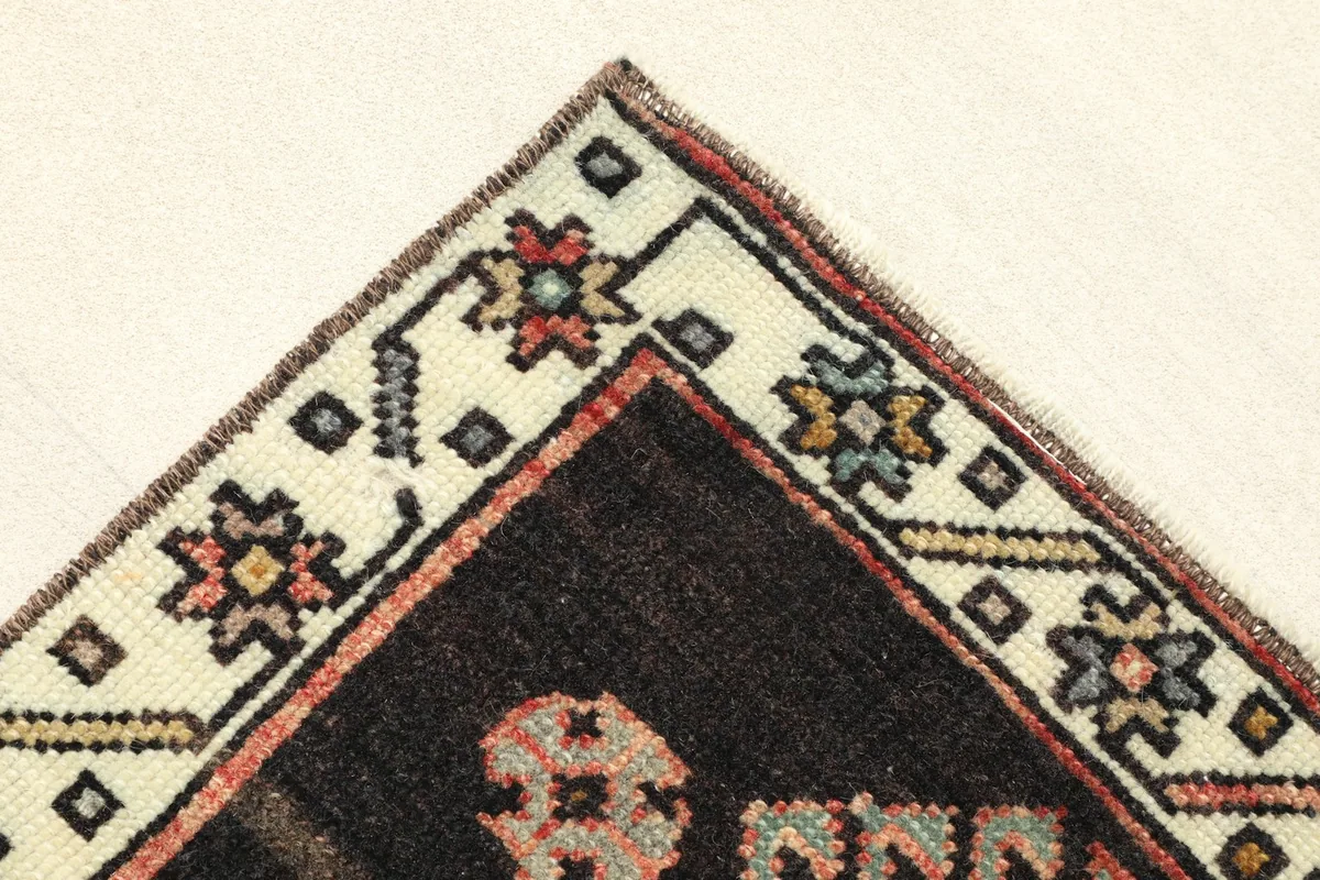 Corner detail showing the ivory border with small floral motifs and the black inner border.