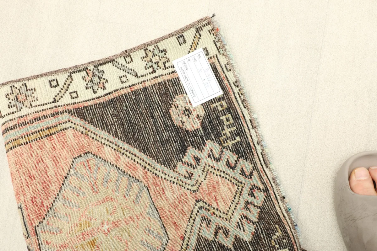 View of the back of the rug near the edge, showing the hand-knotted foundation and a small tag.
