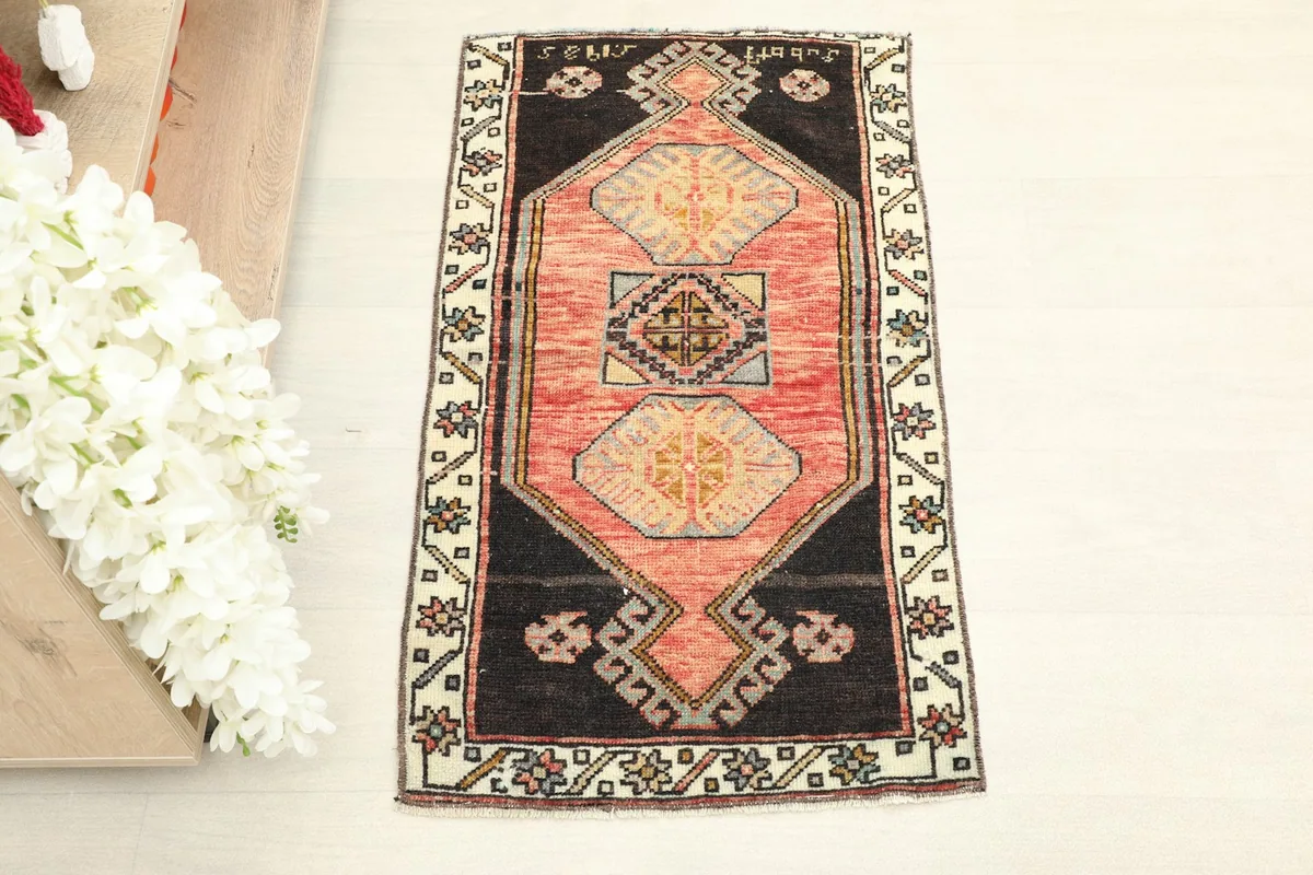 Overhead view of the small rose and black geometric rug, showcasing its full pattern.