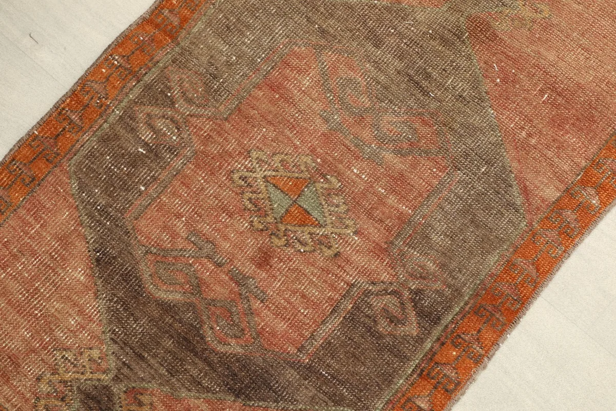 Angled view highlighting the central geometric medallion and orange border of the rug.